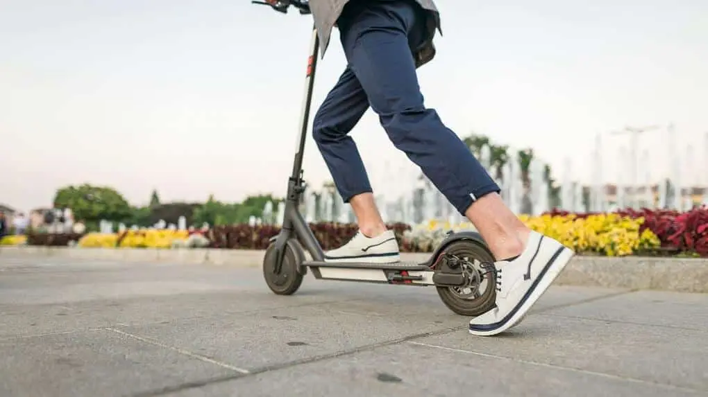 Young man kicking off an e-scooter