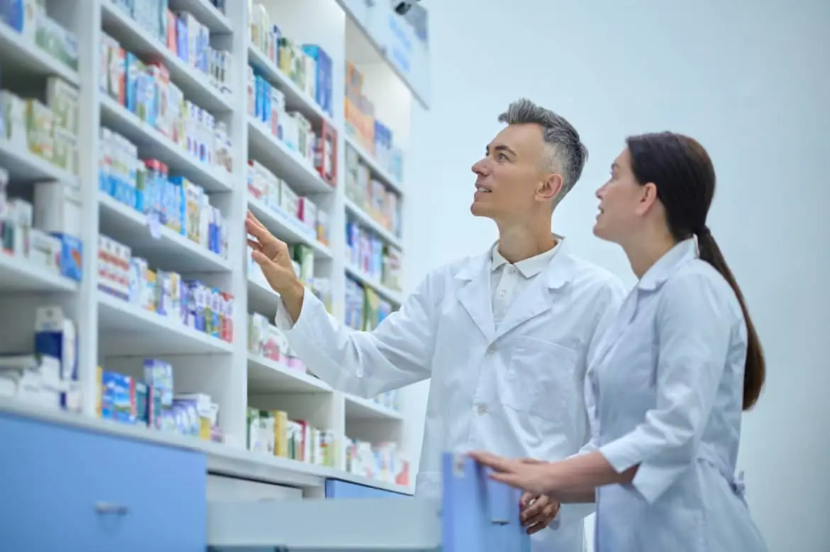 Two druggists in lab coats in the process of inventory in a drugstore industrie pharmaceutique
